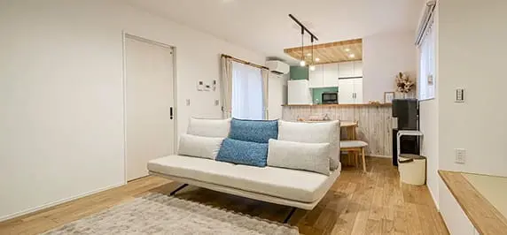 白い壁と木目フローリングが温かみを与えるリビングダイニング。コンパクトながらも居心地の良い空間に、シンプルな家具が調和している。