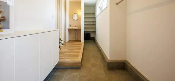 広々とした玄関と土間収納スペース。段差を活かした設計で、奥には収納棚が並ぶシューズクロークを備えている。