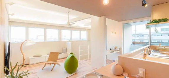 広々とした2階リビング空間。大きな窓から光が差し込み、白を基調としたインテリアに木のぬくもりが調和。リラックスチェアやデザイン性の高い家具が配置されている。