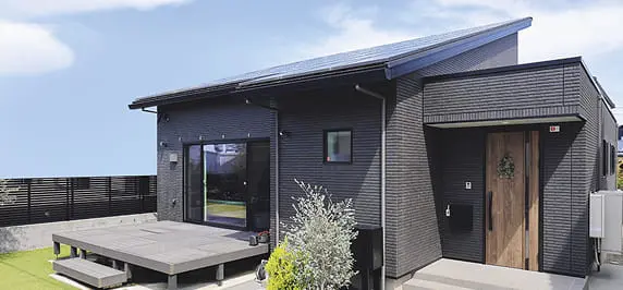 黒を基調としたモダンな平屋住宅。広いウッドデッキと植栽が調和し、落ち着いた雰囲気を感じさせるデザイン。