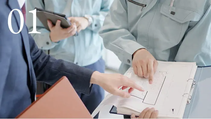 建築関係者が設計図面を見ながら打ち合わせしている様子。施工や現場確認のミーティング風景。